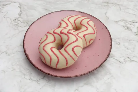 Zwei weiß glasierte Donuts mit pinken Zuckerlinien